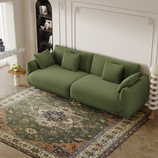 Un canapé en laine verte Teddy de 86,6 pouces avec quatre coussins et des pieds en quincaillerie qui peuvent s'asseoir confortablement dans une chambre d'appartement avec